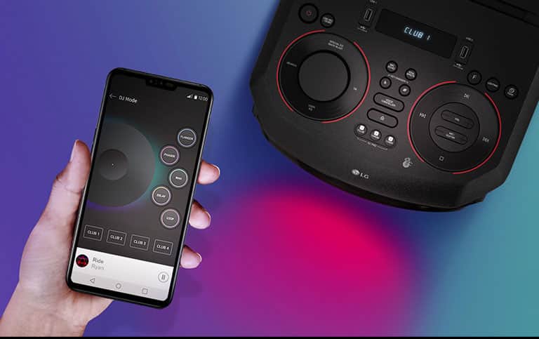 Ręka trzymająca smartfon obok urządzenia LG XBOOM widzianego z góry.