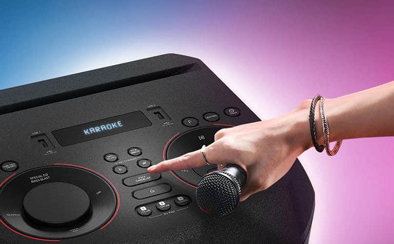 Ręka trzymająca mikrofon próbująca nacisnąć przycisk Voice Canceller u góry urządzenia LG XBOOM.