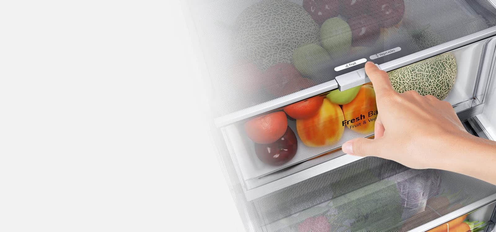 Dolne szuflady lodówki są wypełnione kolorowymi, świeżymi produktami. Wstawiony obraz powiększa dźwignię sterującą, która pozwala wybrać optymalny poziom wilgotności, aby zachować świeżość produktów.