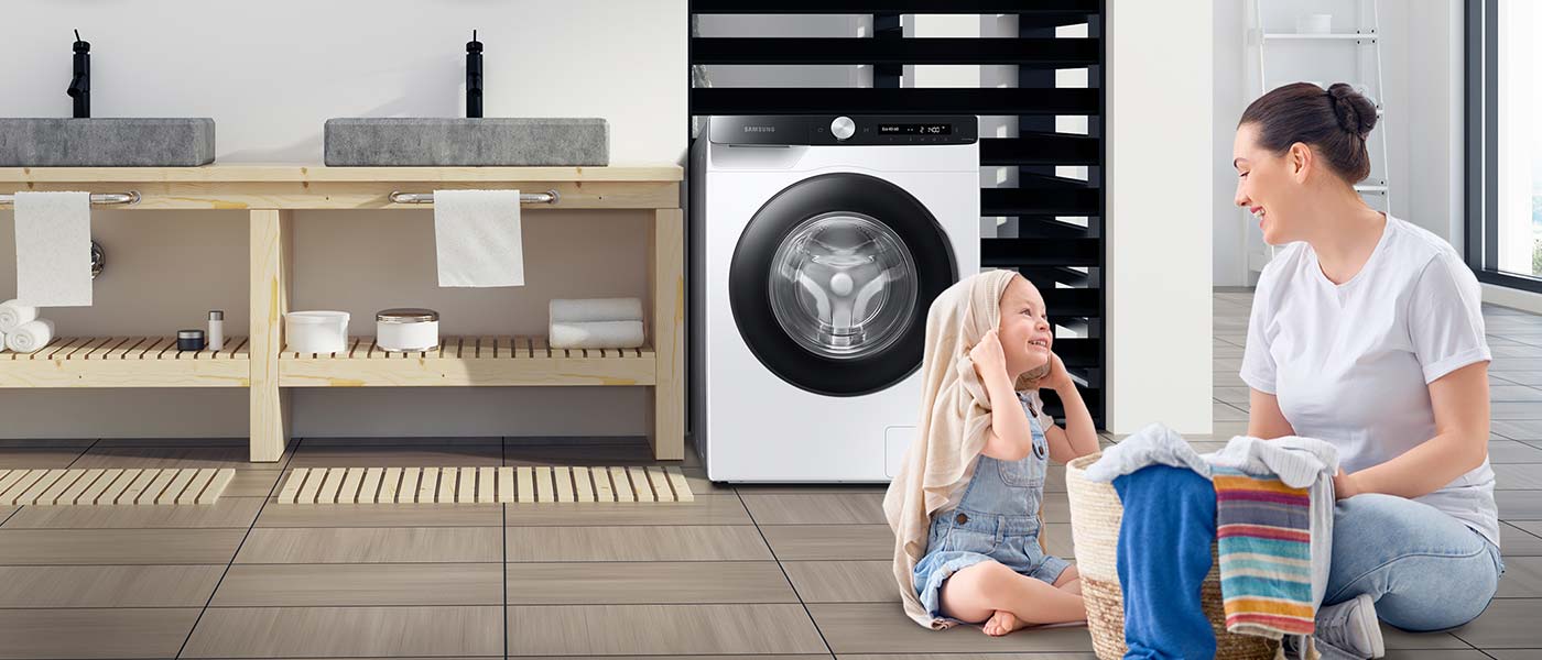 Mama i dziecko siedzą na podłodze w łazience Dziecko z mamą w pralni obok pralki Samsung WW80T534DAEAS6