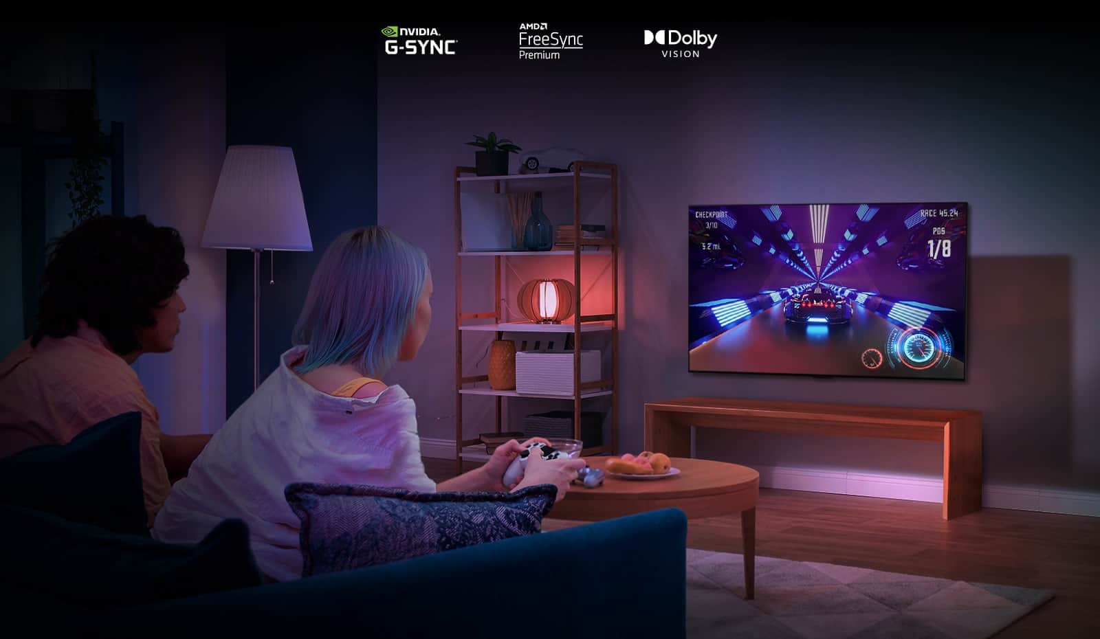 Dwie osoby siedzące na kanapie i grające w grę wyścigową przy użyciu kontrolera na telewizorze LG OLED G2 w salonie