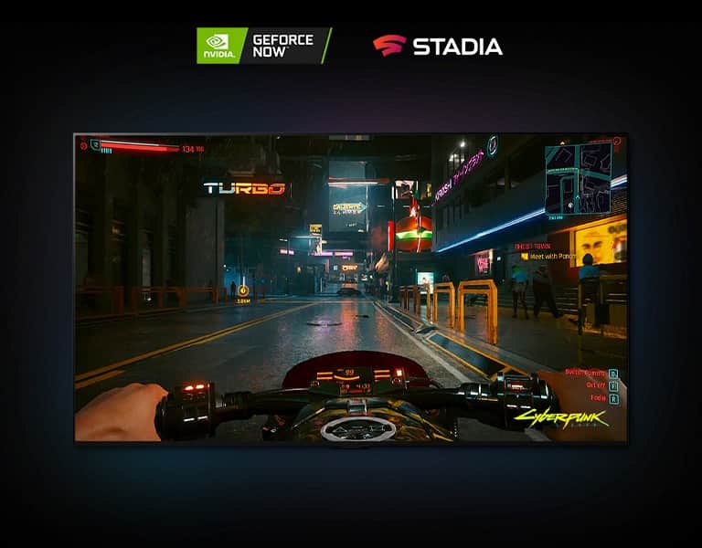 W scenie z gry Cyberpunk 2077 pokazanej na ekranie telewizora LG OLED gracz jedzie oświetloną neonami ulicą na motocyklu