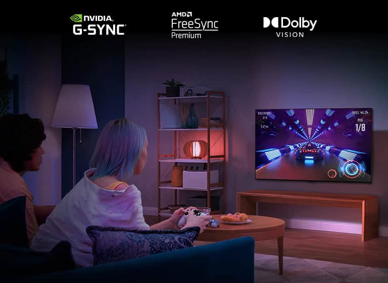 Dwie osoby siedzące na kanapie i grające w grę wyścigową przy użyciu kontrolera na telewizorze LG OLED G2 w salonie