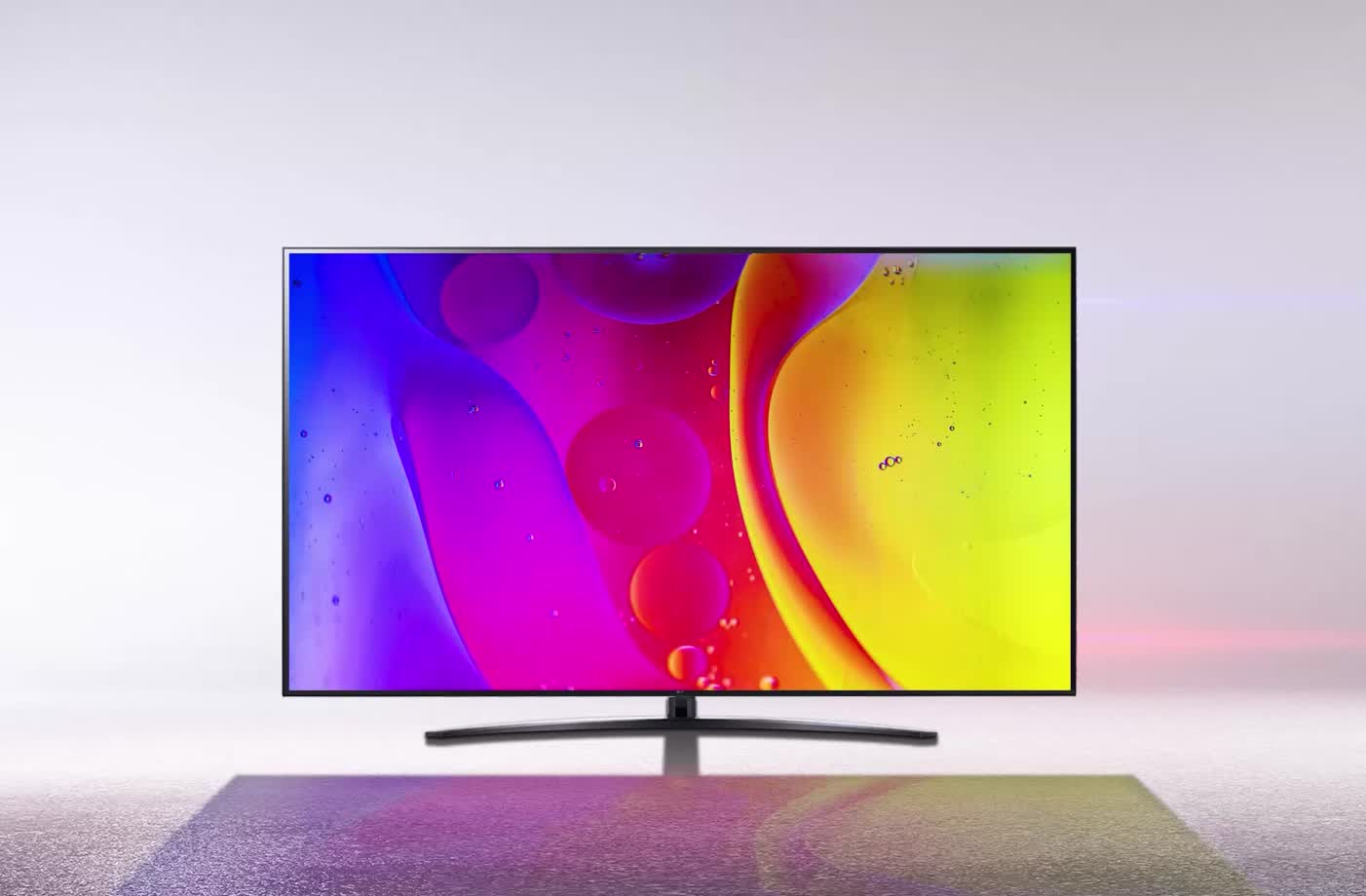 Telewizor w olśniewająco białym pokoju wyświetla jasne, hipnotyzujące kolory na ekranie.