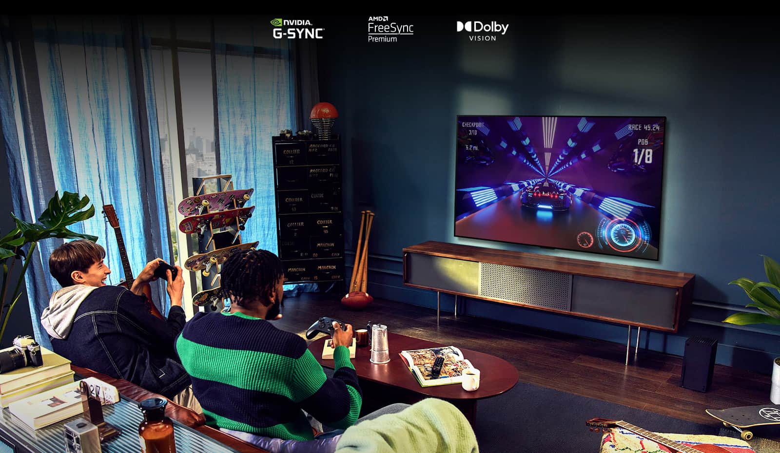 Dwie osoby siedzące na kanapie i grające w grę wyścigową przy użyciu kontrolera na telewizorze LG OLED G2 w salonie