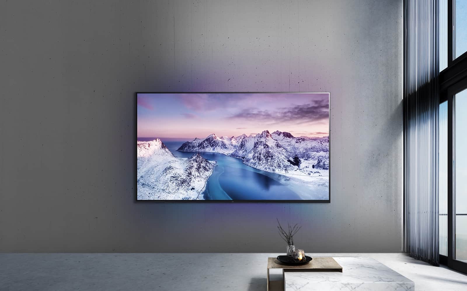 Ultraduży telewizor UHD zawieszony na ścianie za stołem z ozdobami w stylu zen.