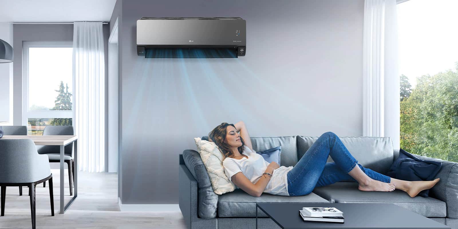 Kobieta leży na kanapie w salonie z klimatyzatorem LG zainstalowanym nad nią na ścianie. Niebieskie strumienie powietrza na obrazie wskazują, że jest on włączony i chłodzi pomieszczenie.