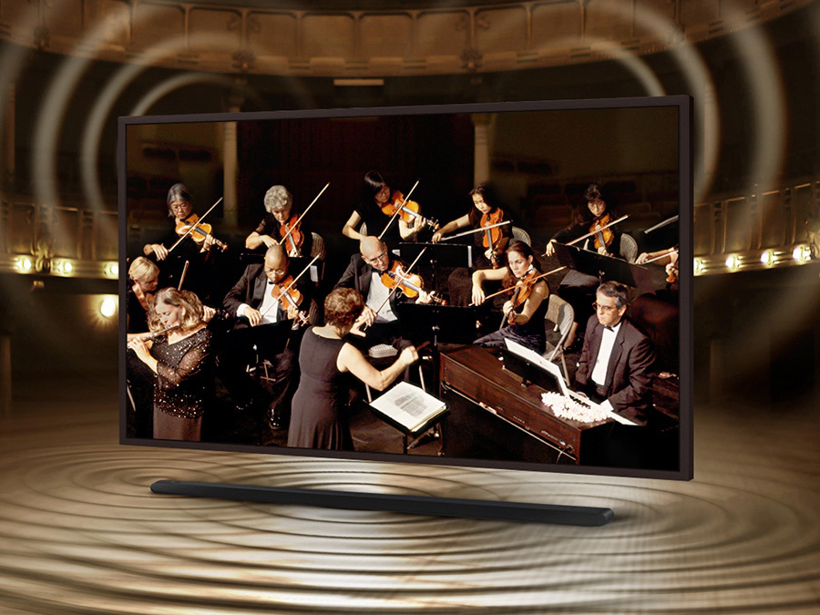 The Frame is showing an orchestra on its screen. The Soundbar is below The Frame with sound ripples coming out of it to show that the sound of the speakers on The Frame and Soundbar are perfectly synced. LS03BBUXXH
