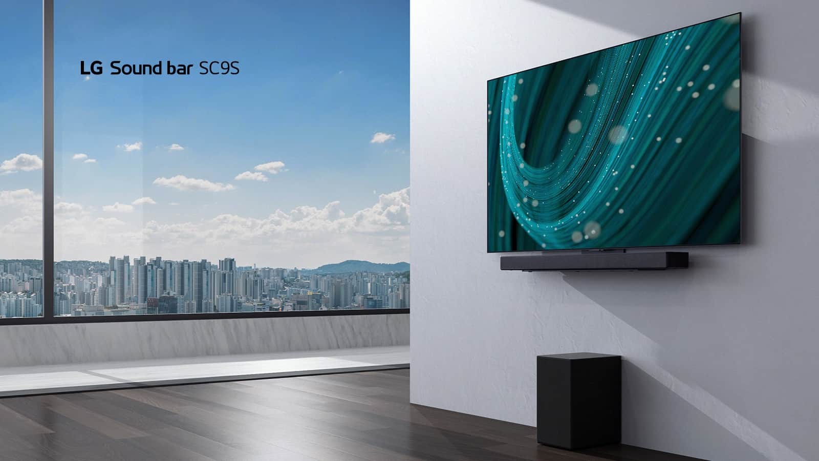 Telewizor i soundbar LG SC9S wiszą na białej ścianie. Pod nimi na podłodze stoi czarny bezprzewodowy subwoofer. Za oknem po lewej stronie widać panoramę miasta i niebieskie niebo.