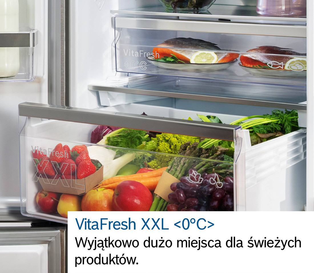 Otwarta chłodziarka z wysuniętą szufladą, w środku której są soczyste, świeże warzywa i owoce.
