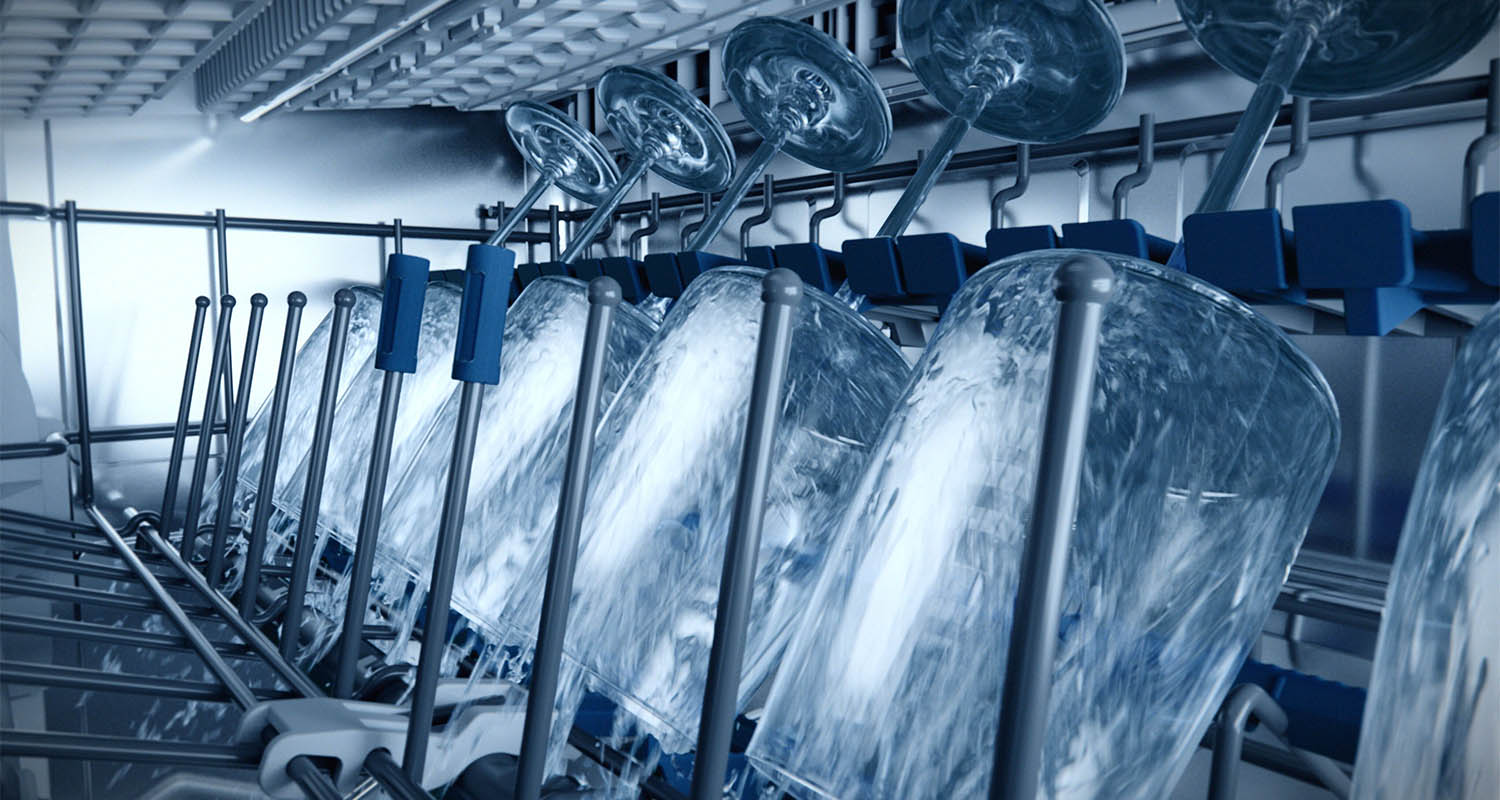 Kieliszki na wino myte w górnym koszu zmywarki strumieniami wody.