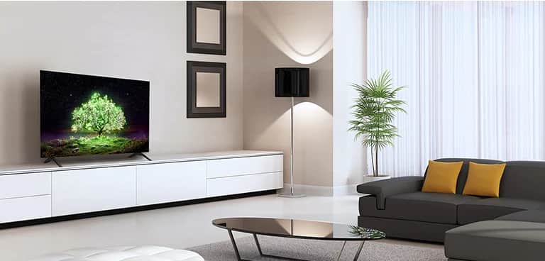 Telewizor OLED A1 w zmysłowo urządzonym pokoju. Na ekranie telewizora widać jasno świecące zielone drzewo.