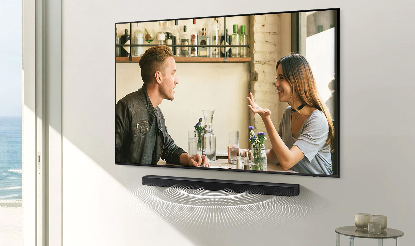 Simulated sound wave graphics leave the soundbar from its center, illustrating the location of the soundbar’s built-in center speaker. An infographic shows the location of the center speaker.