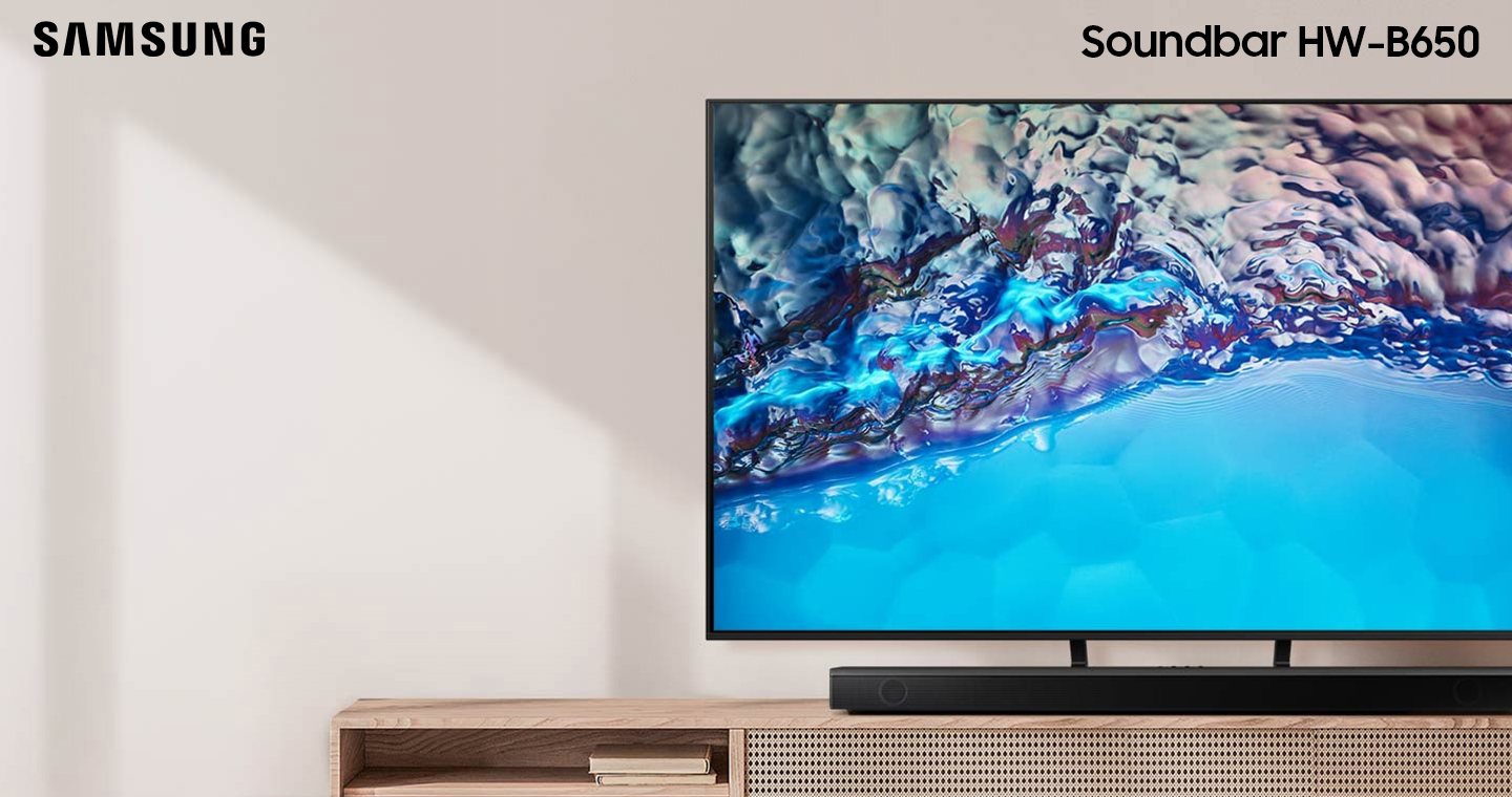 Samsung B series Soundbar and subwoofer are positioned with Crystal UHD TV on living room cabinet.